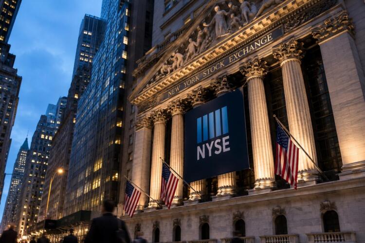 Fachada iluminada de la Bolsa de Nueva York al anochecer.