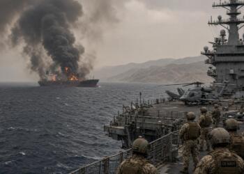 Militares observan desde un buque de la US Navy un barco petrolero incendiado en alta mar.