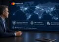 Un ejecutivo observa una pantalla de Mastercard con un mapamundi y datos de pagos.