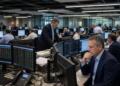 Operadores financieros trabajan en una amplia sala con múltiples pantallas y monitores.