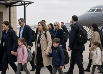 Un grupo de adultos y niños caminan por una pista de aterrizaje junto a un avión.