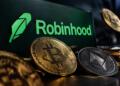 Logotipo de Robinhood junto a monedas de Bitcoin y Ethereum físicas.