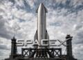 Logo de SpaceX frente a cohete Starship en plataforma de lanzamiento.